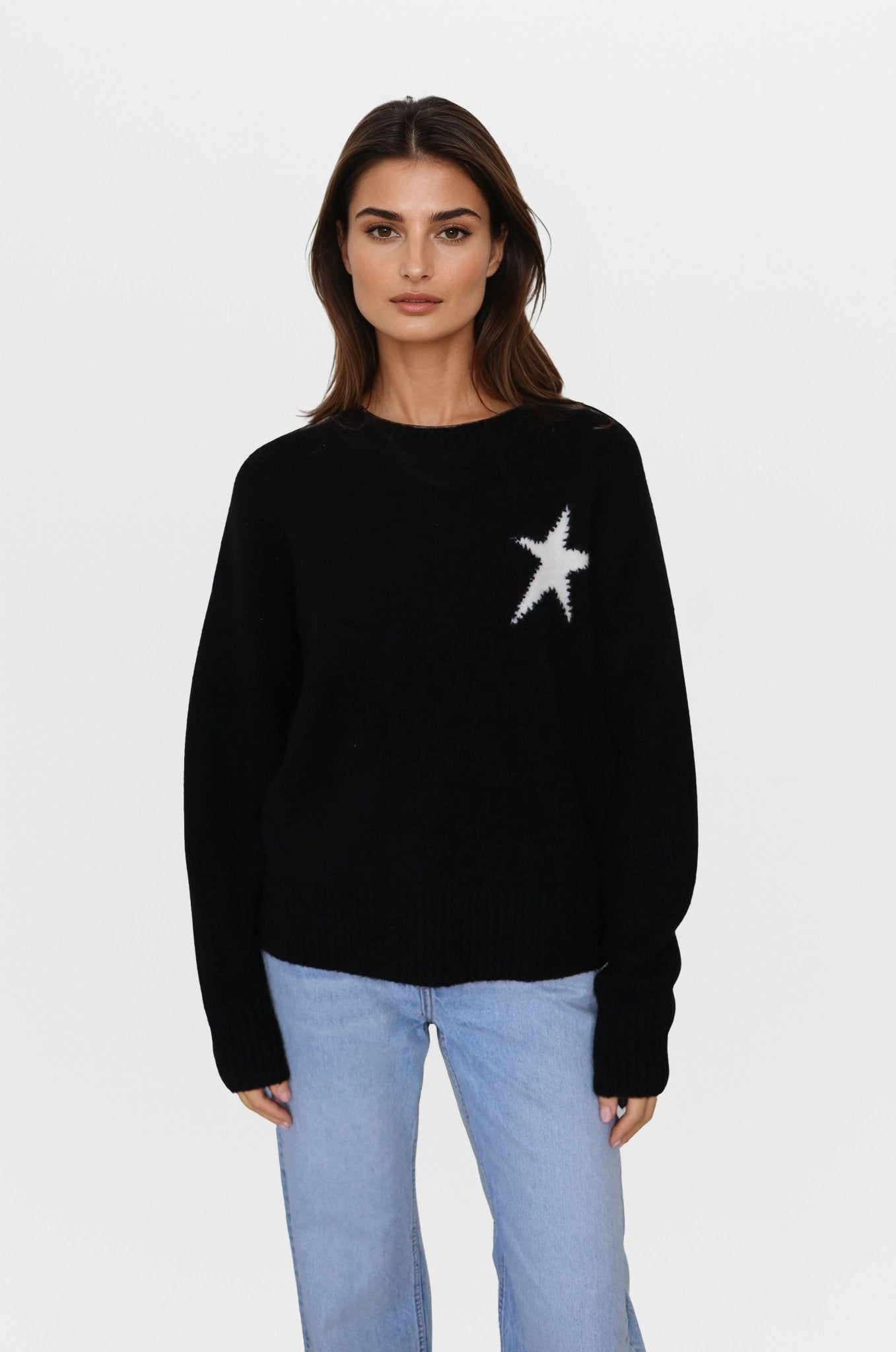 Woman wearing a black sweater with a white star design on a light gray background