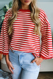 Person wearing a red and white striped sweater with bell sleeves and light blue jeans.