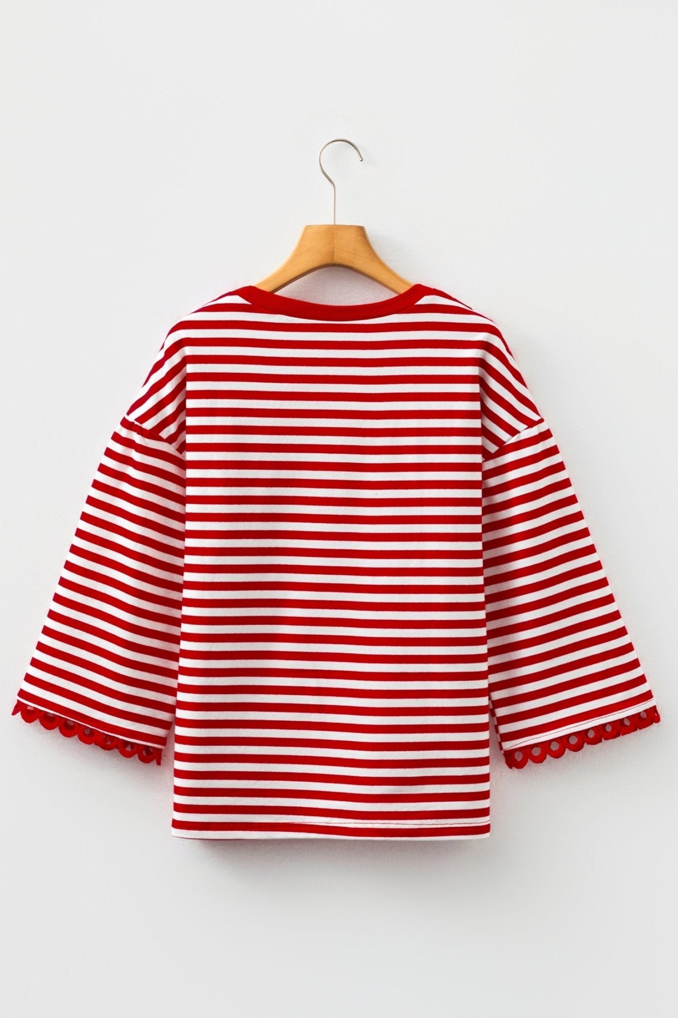 Red and white striped sweater on a wooden hanger against a white background
