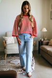 Woman wearing a red and white striped shirt and blue jeans in a living room.