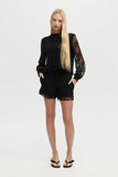Woman wearing a black outfit with lace sleeves and shorts on a white background