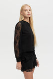 Woman wearing a black outfit with lace sleeves on a white background