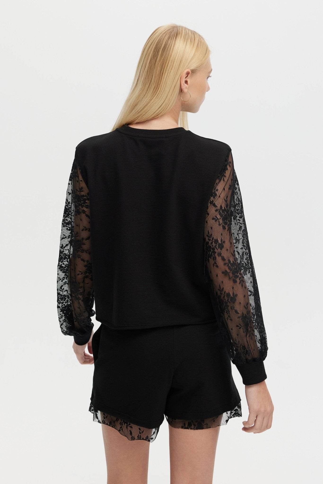Black outfit with lace sleeves and shorts on a white background