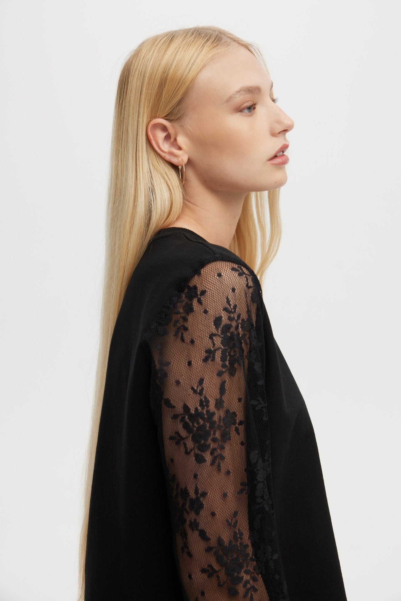 Woman wearing a black lace top against a white background