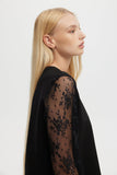 Woman wearing a black lace top against a white background