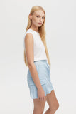 Woman wearing a white sleeveless top and light blue shorts on a white background