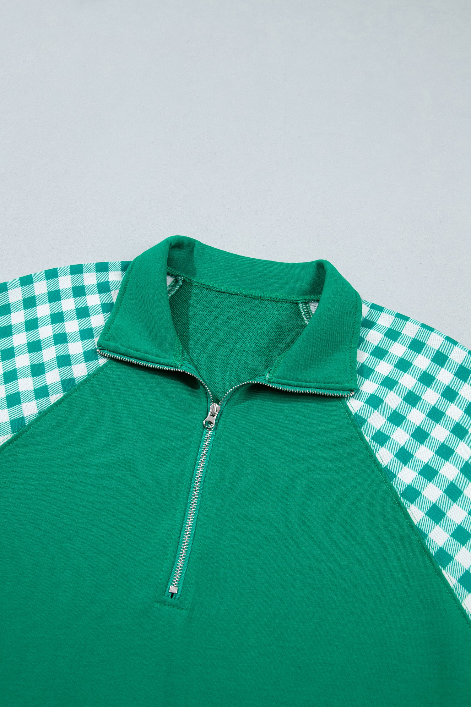 Dark green quarter zip sweatshirt collar and metal zipper, close-up