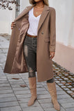 Person wearing a long brown coat, white shirt, black pants, and tan boots on a sidewalk.