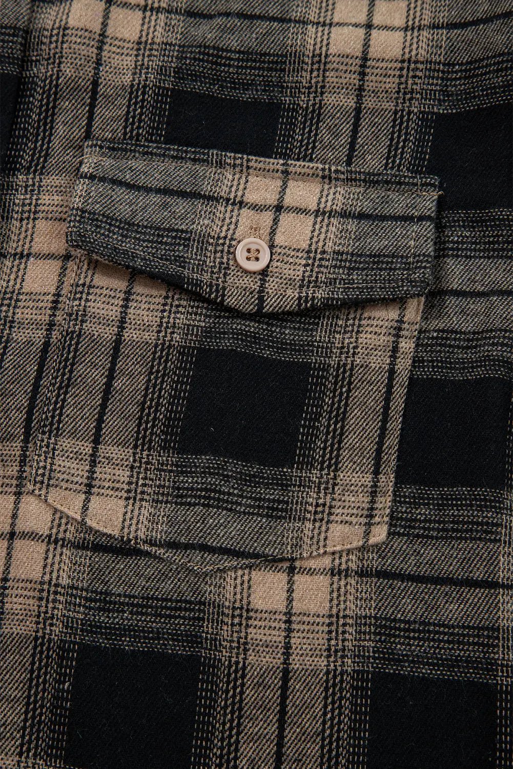 Close-up of a plaid shirt with a button on a pocket
