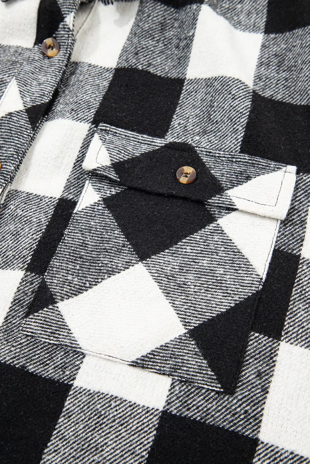 Close-up of a black and white checkered shirt with a button detail.