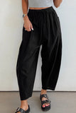 Person wearing black wide-leg pants and a gray top against a white background