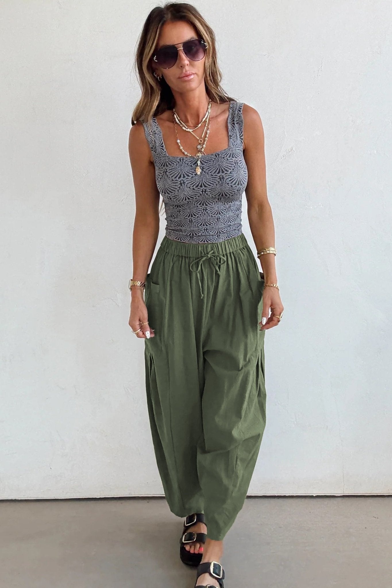 Woman wearing a sleeveless top and wide-leg pants against a white background