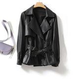 Black leather jacket on a hanger with a purple bag in the background
