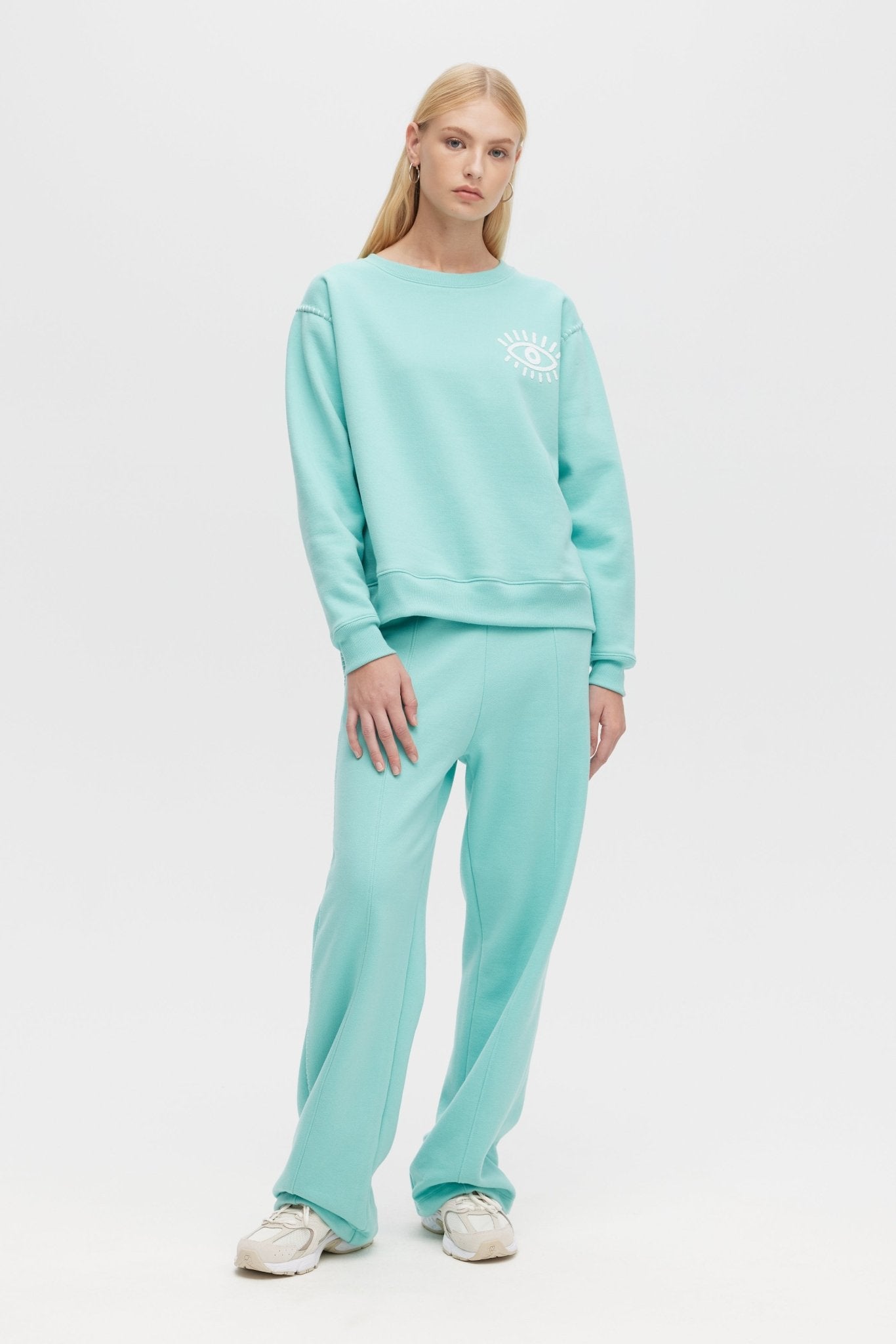 Woman wearing a light blue sweatshirt and pants set on a white background
