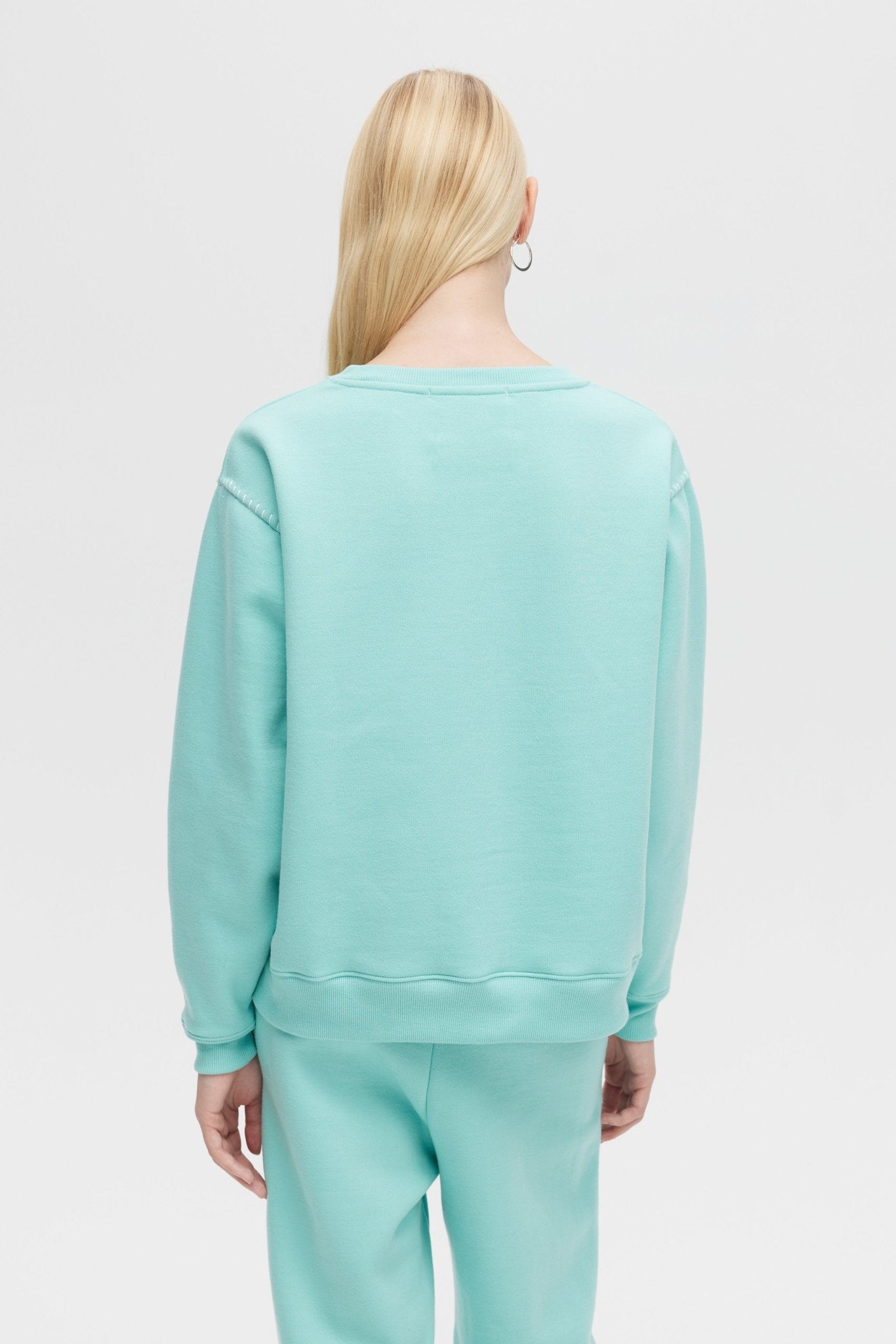 Person wearing a light blue sweatshirt and pants on a white background