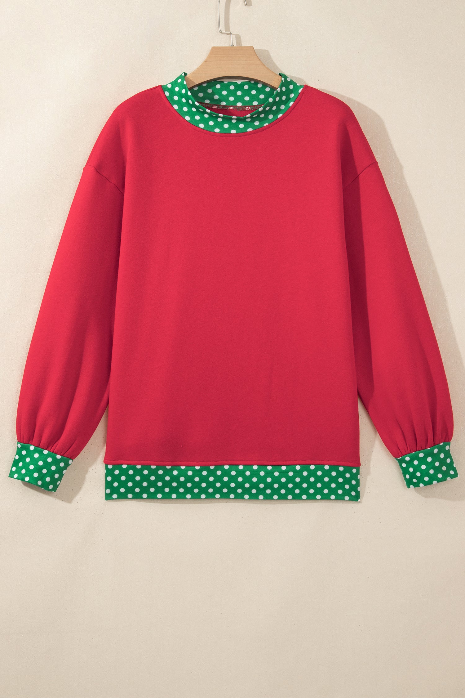 Red sweatshirt with green-white polka-dot trim at collar, cuffs, and hem.