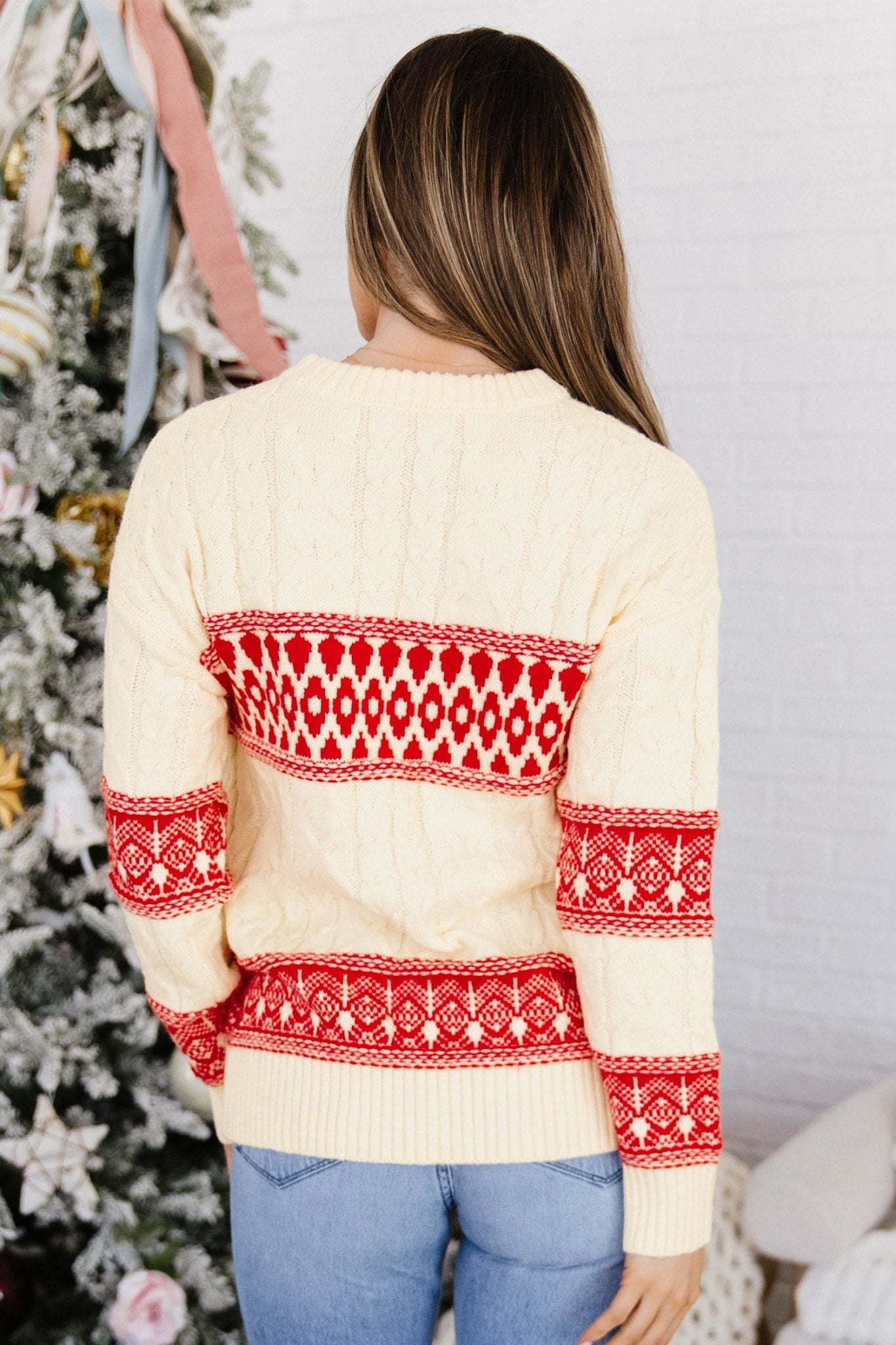 Back view of woman in cream Fair Isle sweater with red-white patterns and jeans.