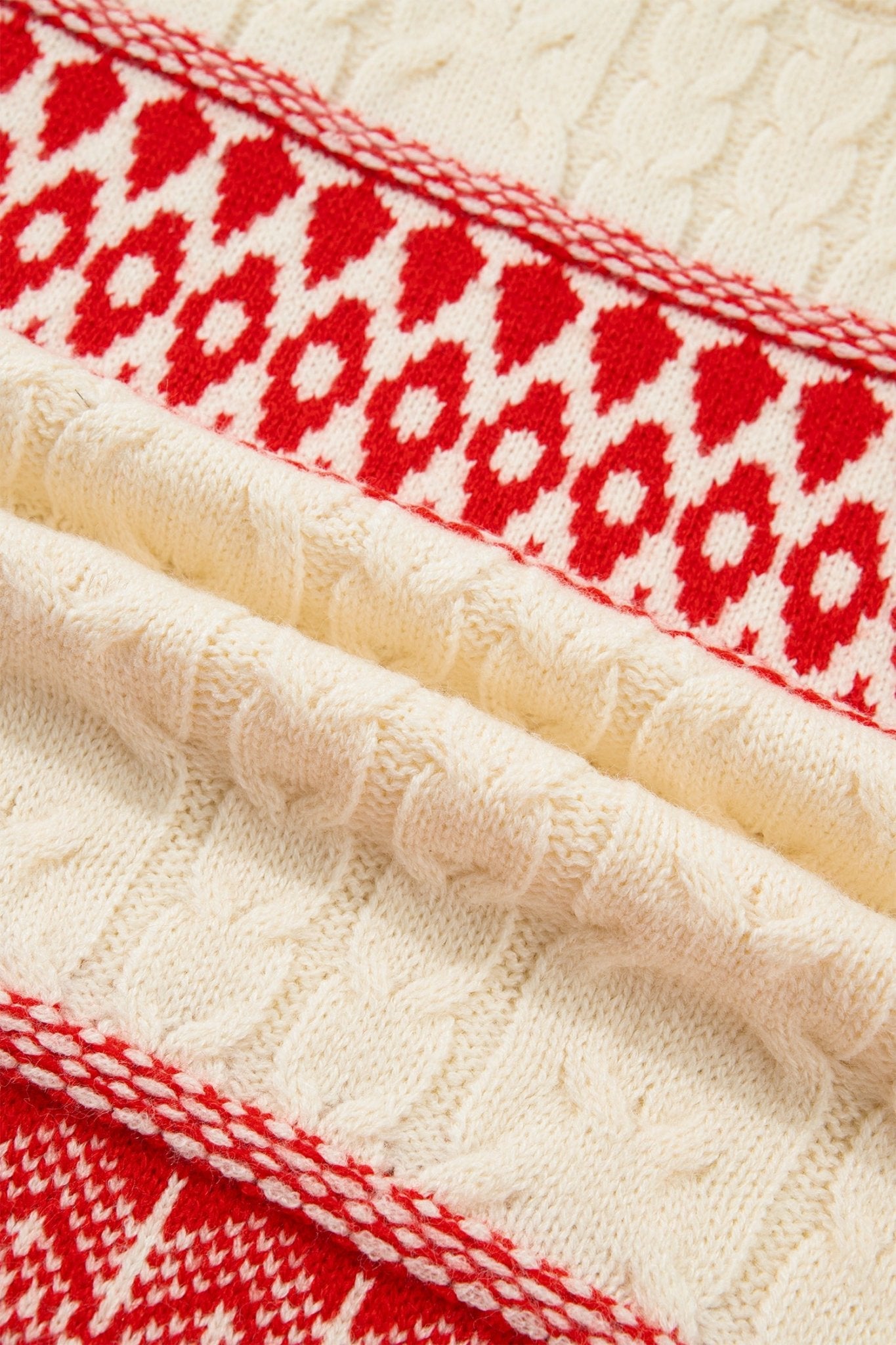 Close-up of a cream-colored cable-knit sweater with a red and cream Fair Isle patterned trim.
