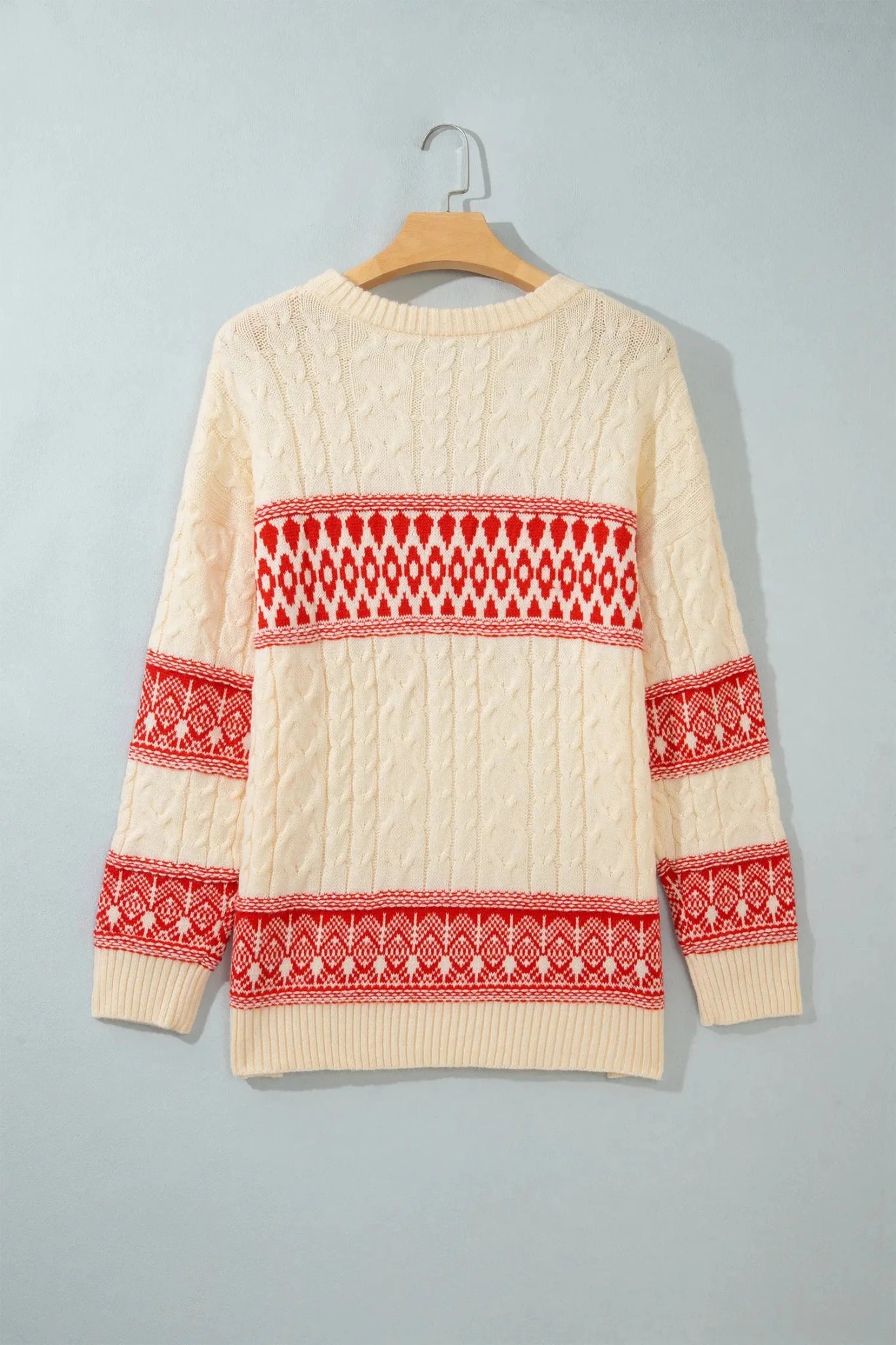 Cream cable-knit sweater with red Fair Isle patterns on chest, cuffs, and hem.
