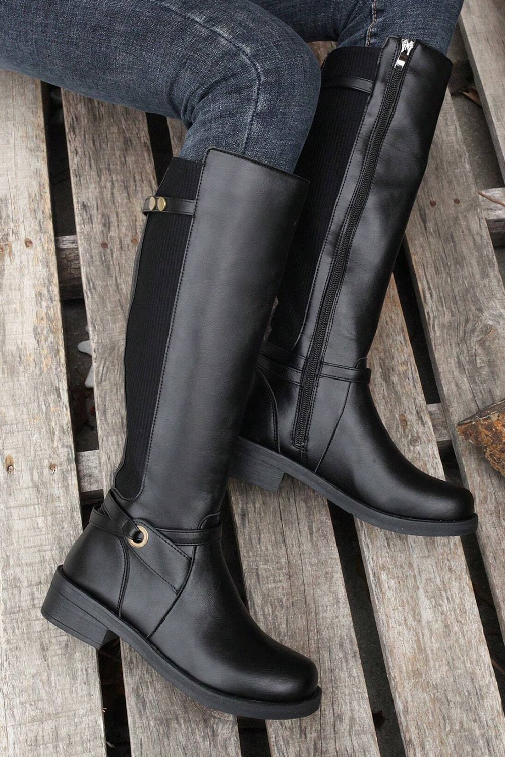 Black knee-high boots on a wooden surface