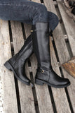 Black knee-high boots on a wooden surface