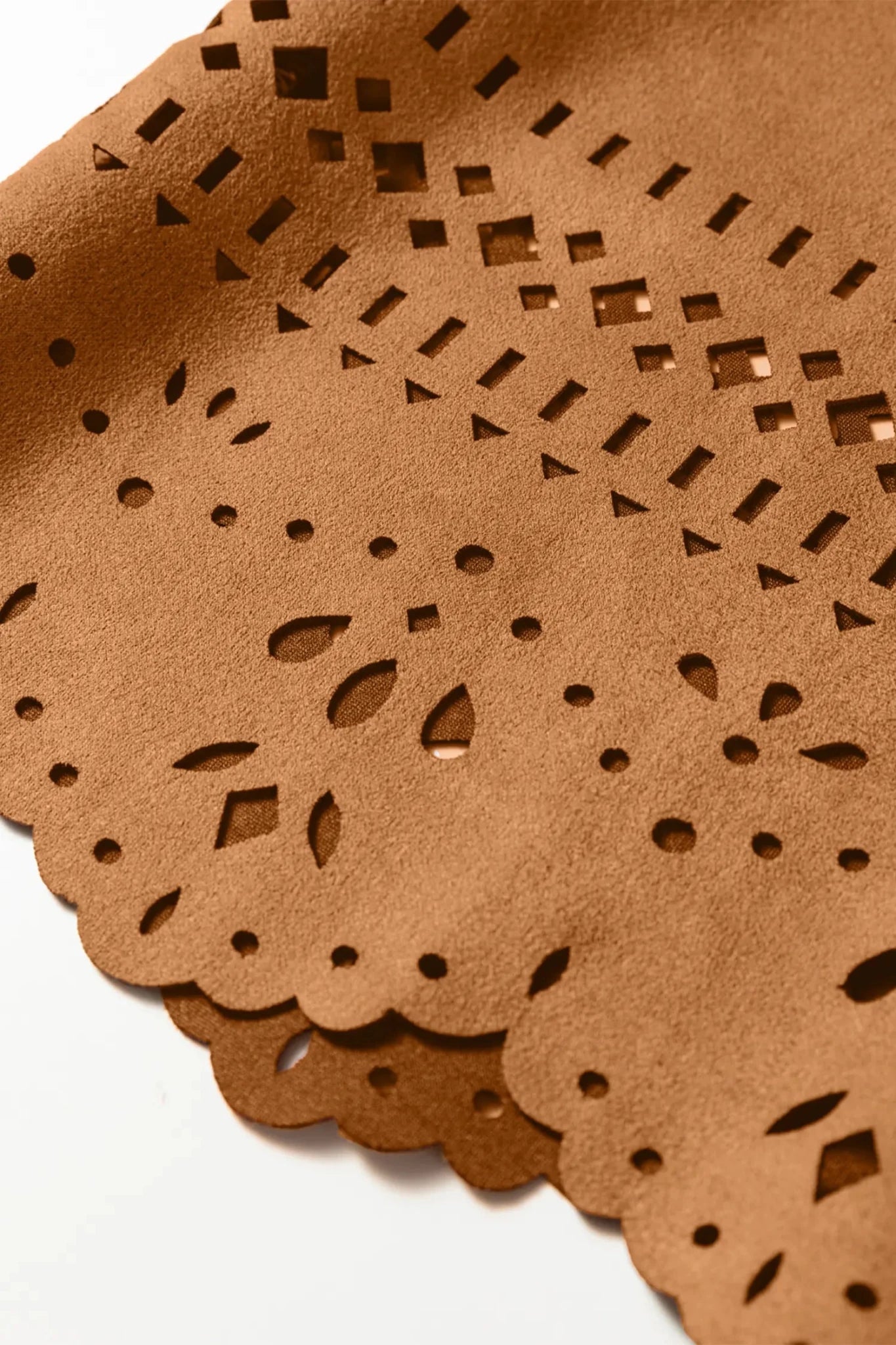 Close-up of brown leather with laser-cut patterns on a white background