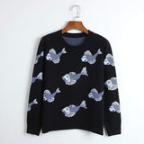 Black sweater with fish pattern on a hanger against a white background