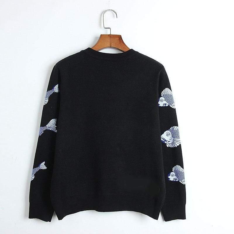 Black sweater with fish patterns on sleeves, hanging on a wooden hanger against a white background.