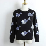 Black sweater with blue fish pattern on a mannequin against a white background