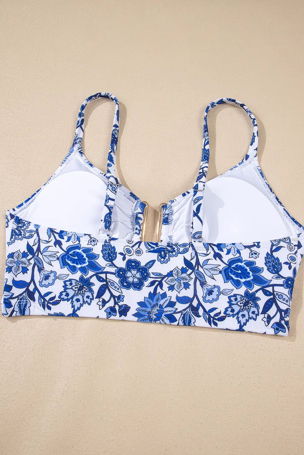 Women’s underwire bra with blue-white floral print cups and lower band, laid flat on beige.