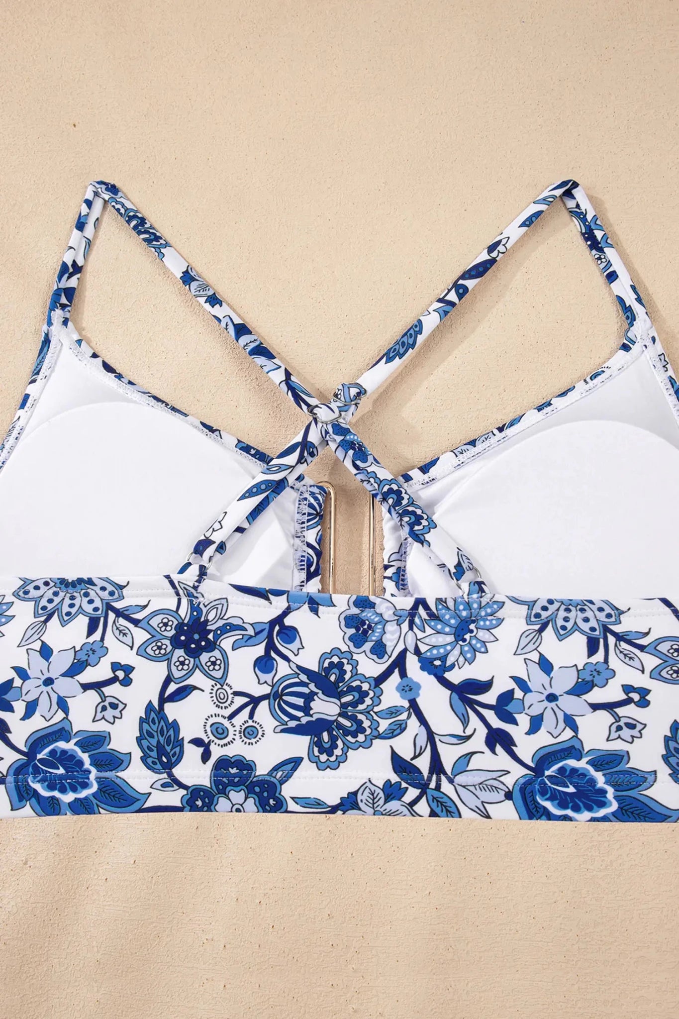 Close-up of white bikini top with blue floral print straps and matching floral band across the lower front.