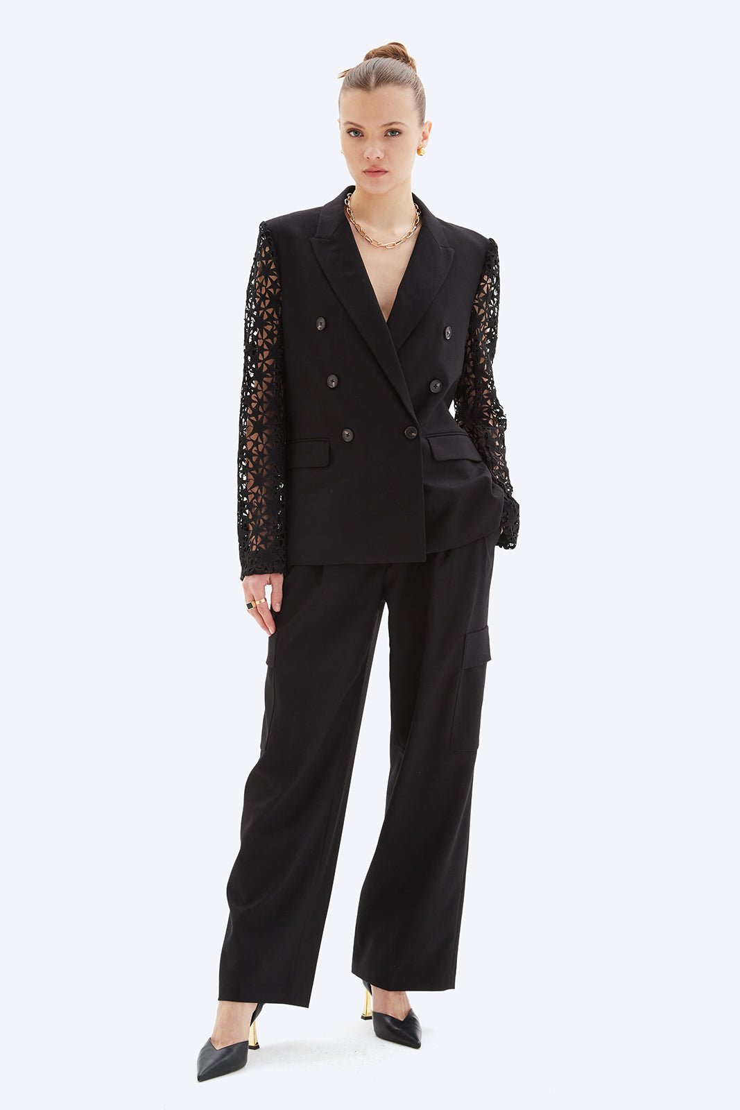 Woman wearing a black suit with lace sleeves on a white background