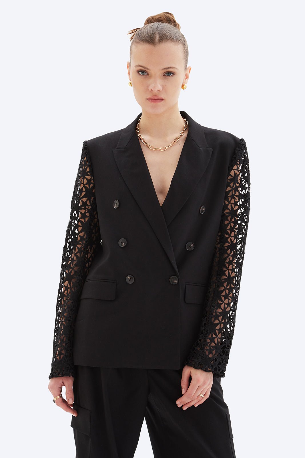Woman wearing a black blazer with lace sleeves on a white background