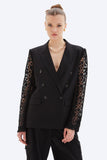 Woman wearing a black blazer with lace sleeves on a white background
