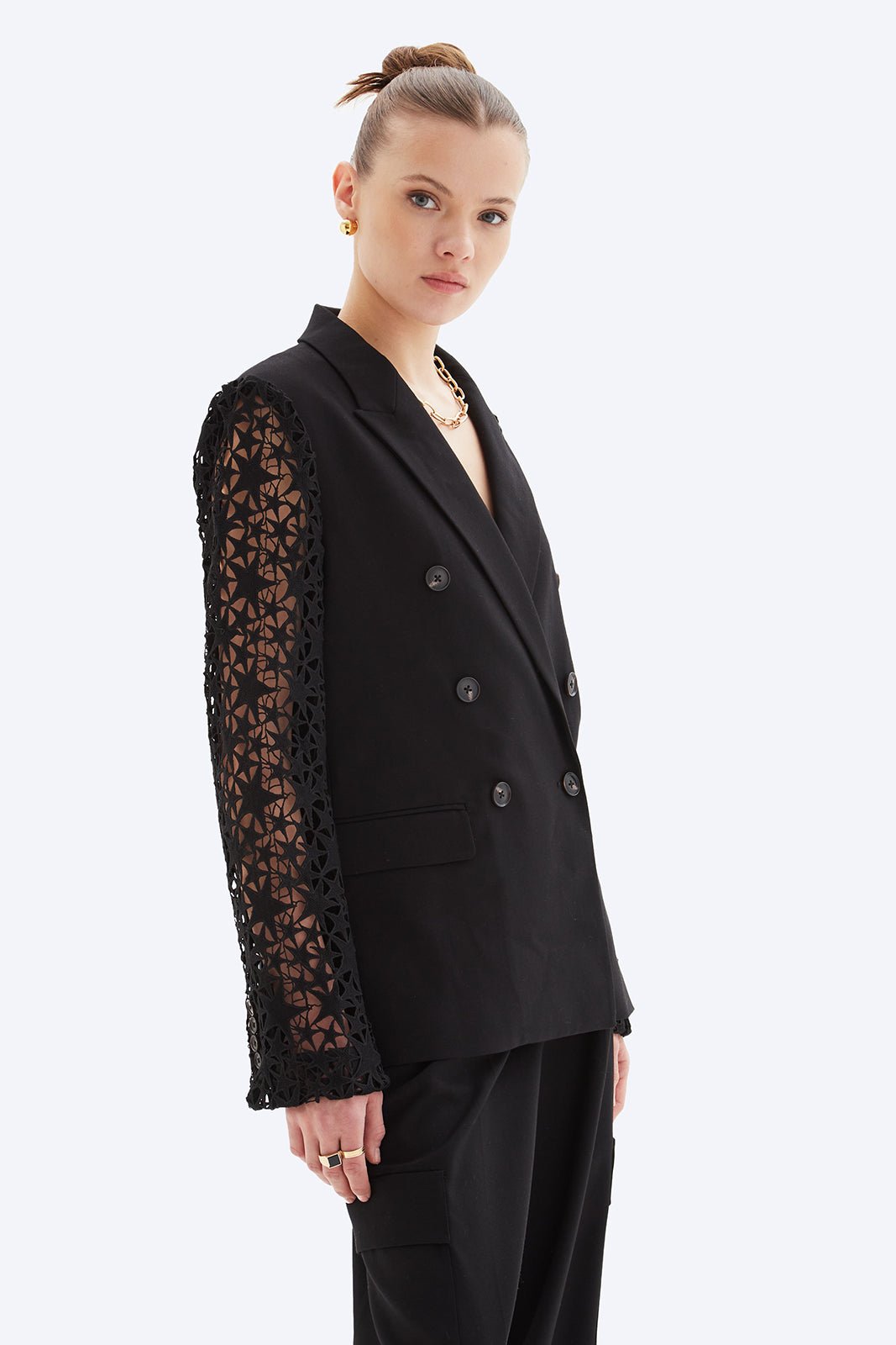 Black blazer with lace sleeves worn by a model on a white background