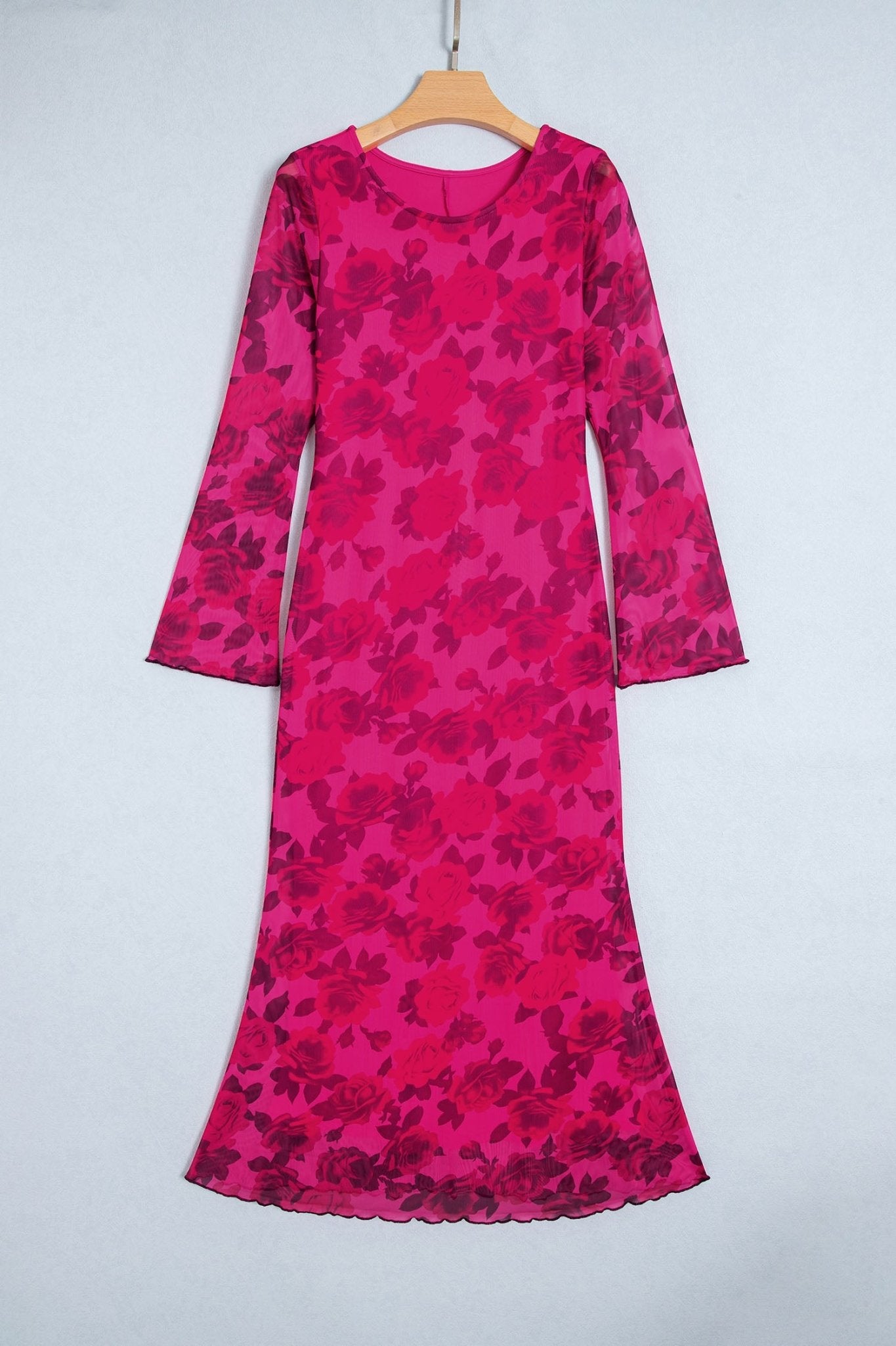 Long-sleeve midi dress in vibrant pink and magenta floral pattern on a wooden hanger against a light gray wall.