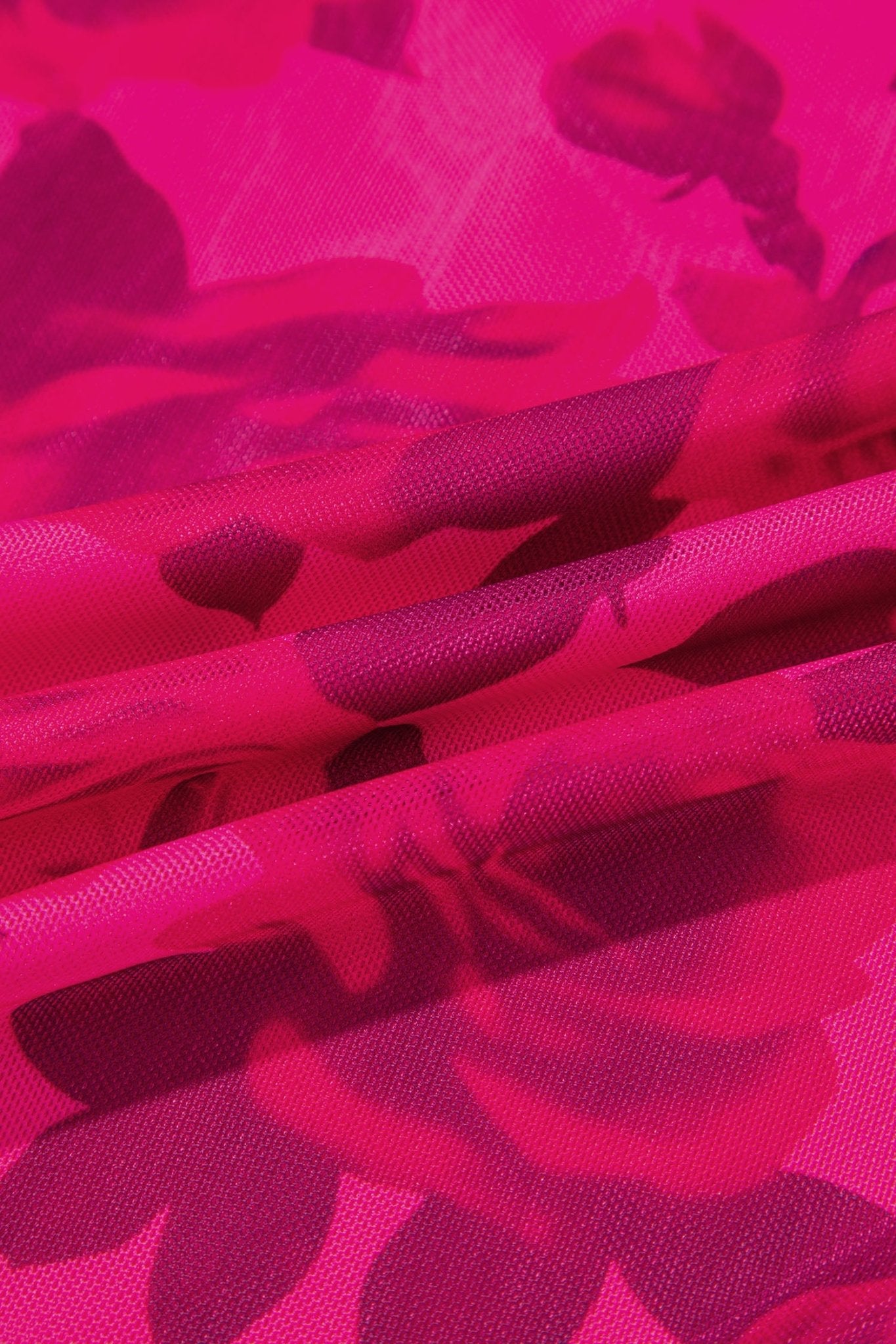A close-up of sheer mesh fabric with a bold floral pattern in vibrant hot pink and magenta tones.