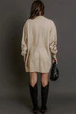 Back view of woman in beige knit sweater dress with cutout sleeves and black boots.