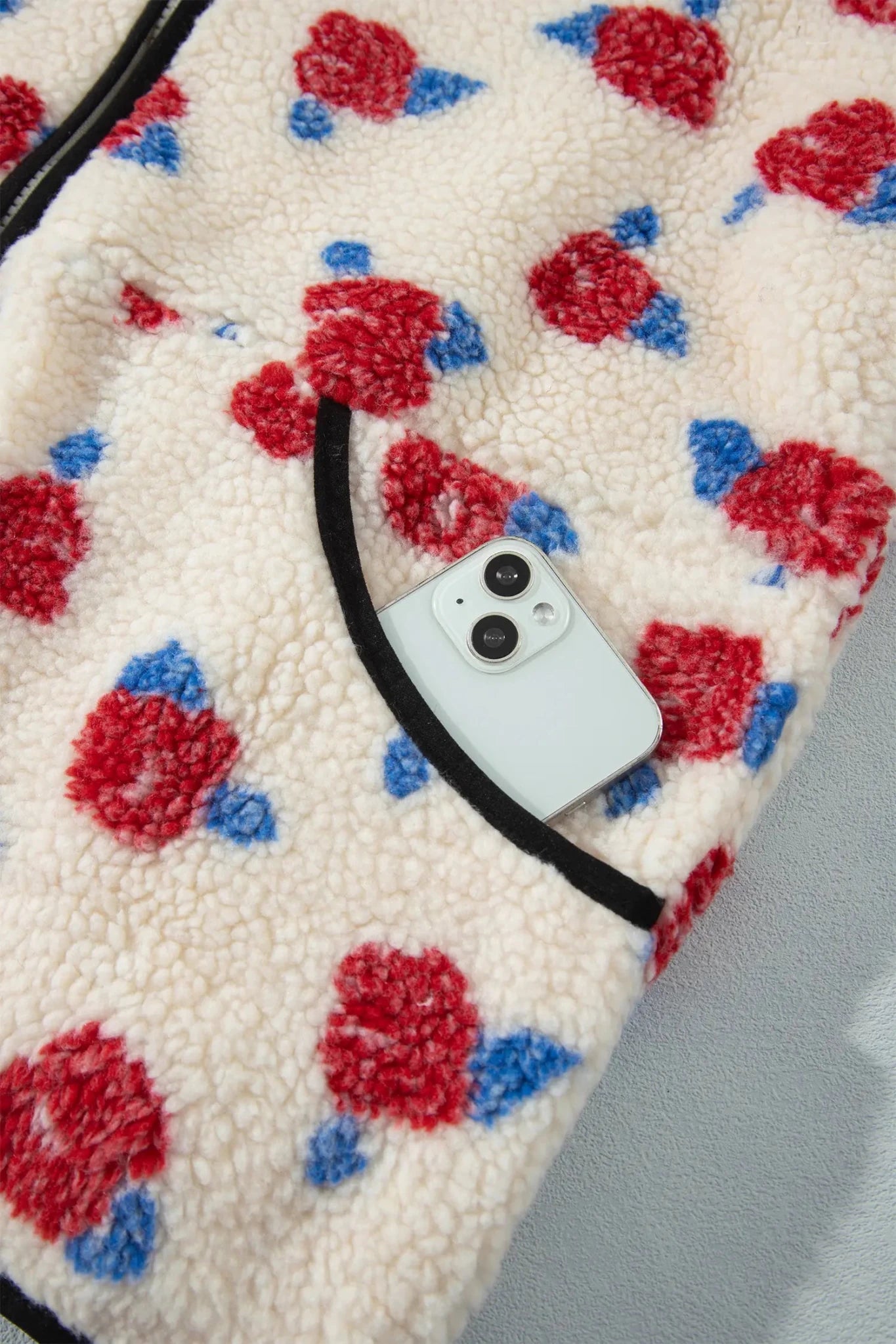 Close-up of creamsherpa pocket with floral print and white smartphone.
