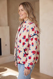 Woman in cream floral sherpa jacket with black trim and light blue jeans.