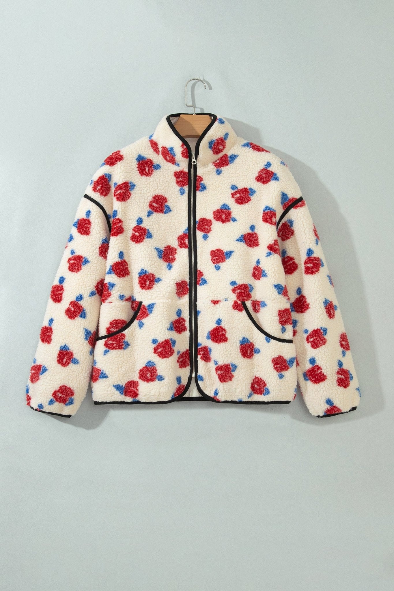 Cream sherpa fleece jacket with red rose pattern and black trim on hanger.