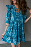 Woman wearing a blue floral dress against a neutral background