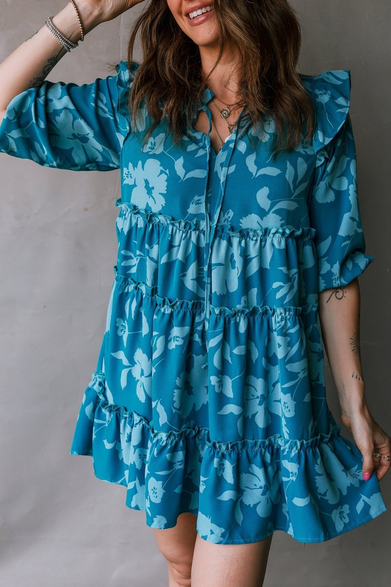 Woman wearing a blue floral dress against a neutral background