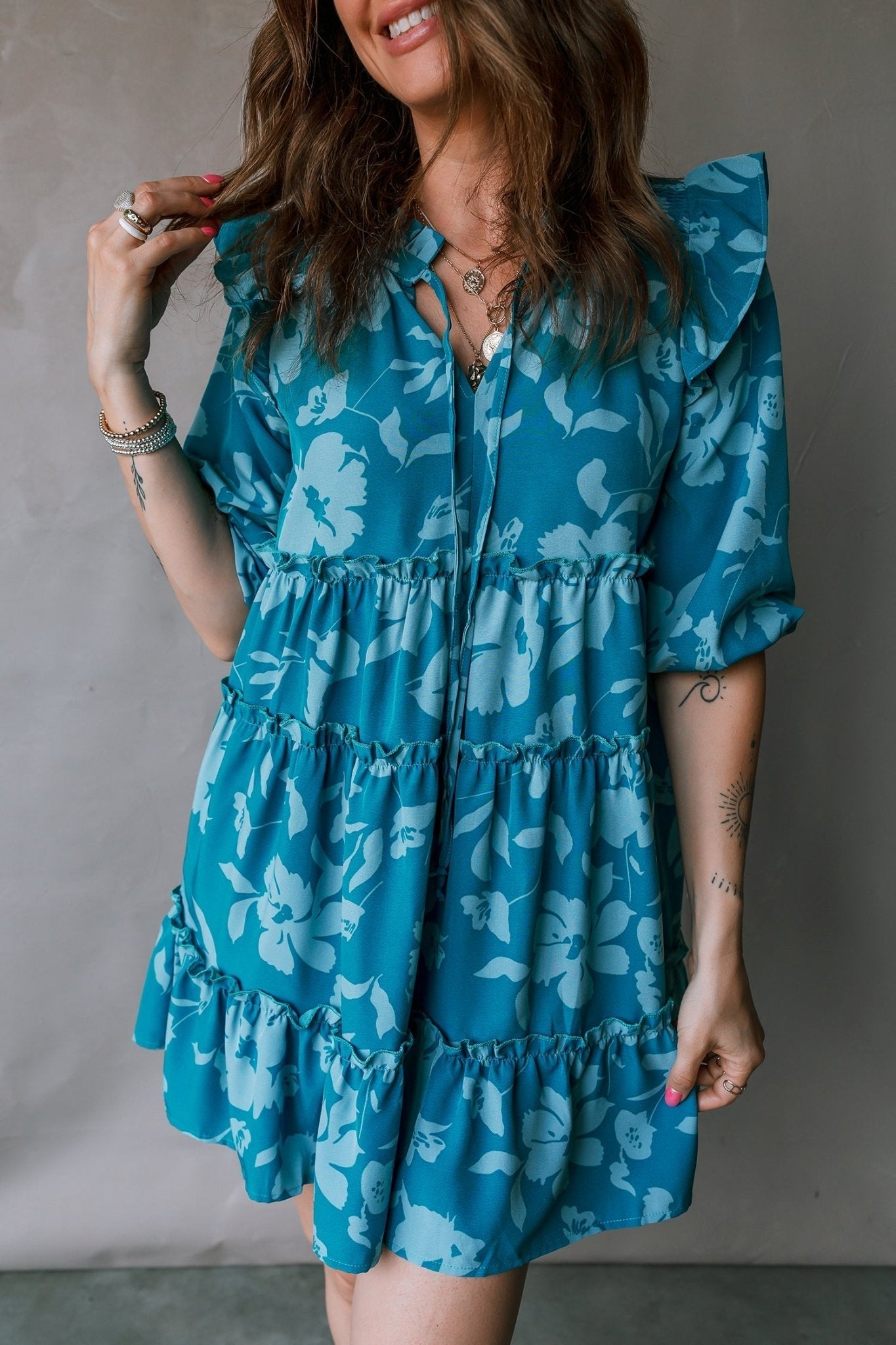 Woman wearing a blue floral dress against a neutral background