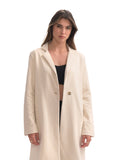 Woman wearing a long beige coat on a white background