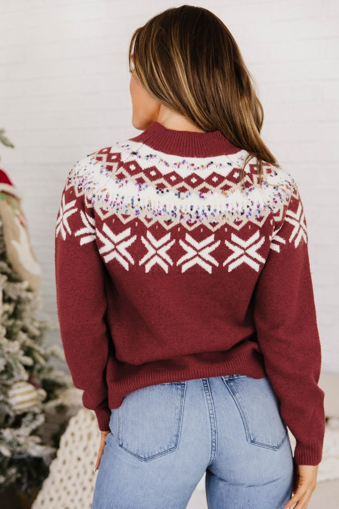 Woman wearing a burgundy Fair Isle sweater with light blue jeans, viewed from behind.
