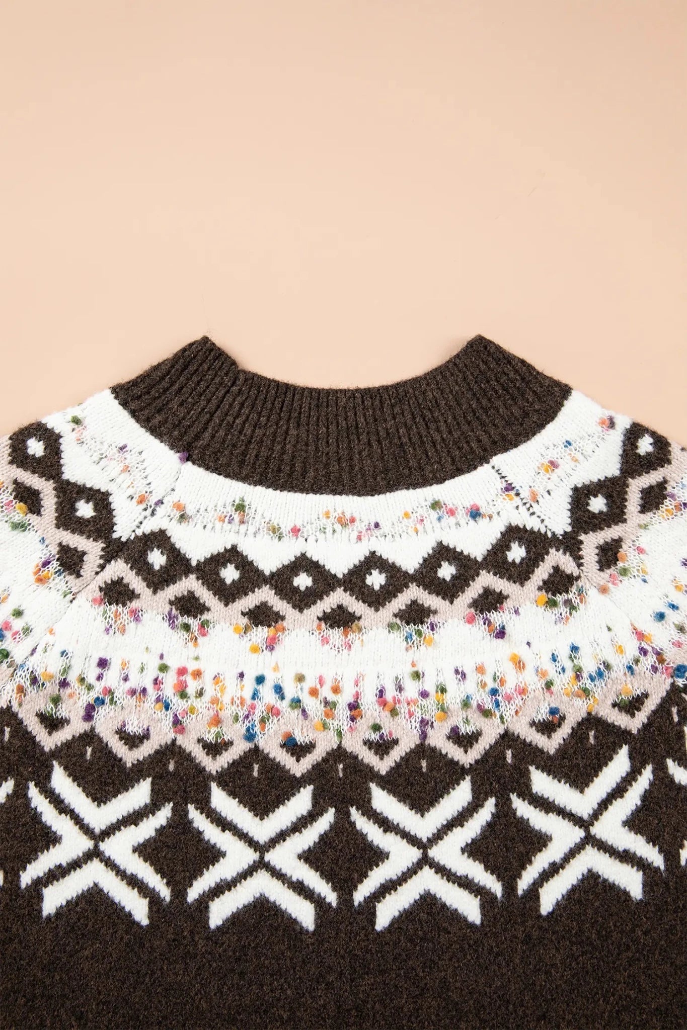 Close-up of a brown knit sweater with a white patterned yoke and colorful speckled band.