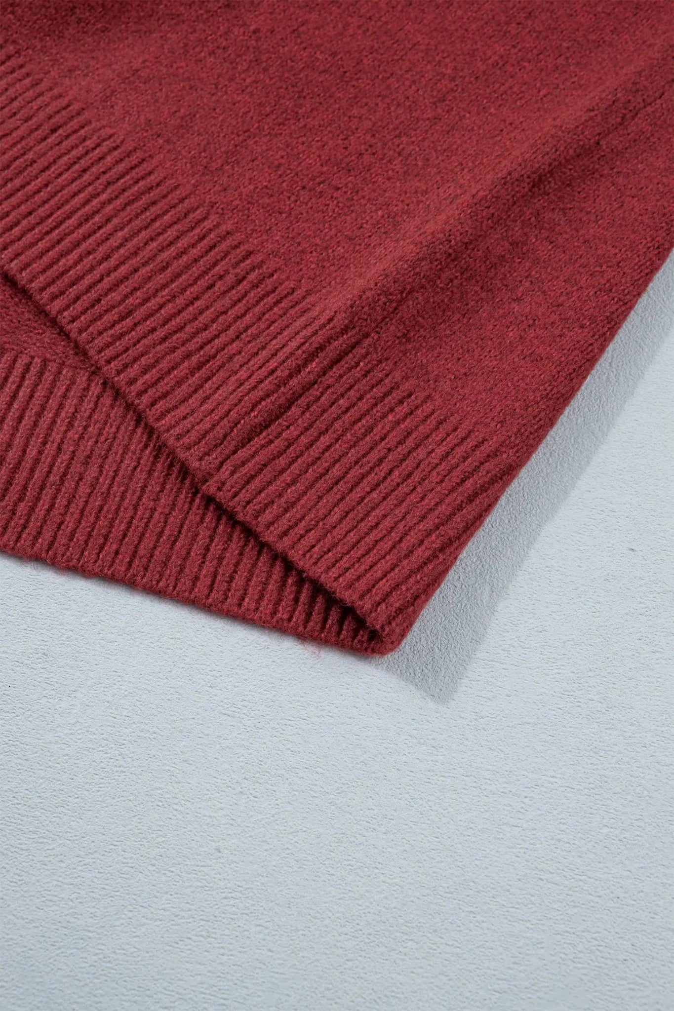 Close-up of folded deep burgundy ribbed knit fabric showing texture and stitching.
