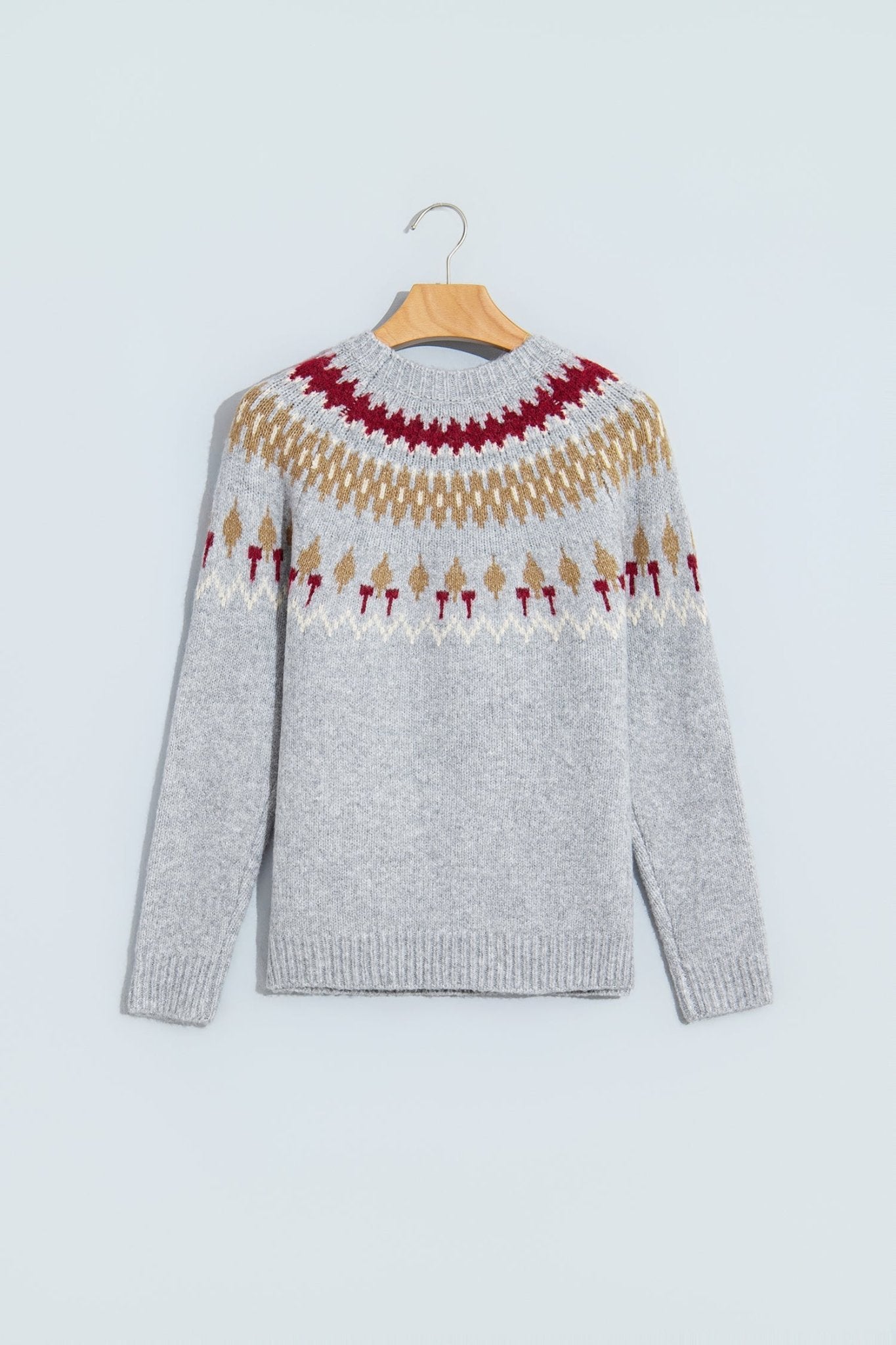 Light gray Fair Isle knit sweater with red, beige, and white pattern on hanger.