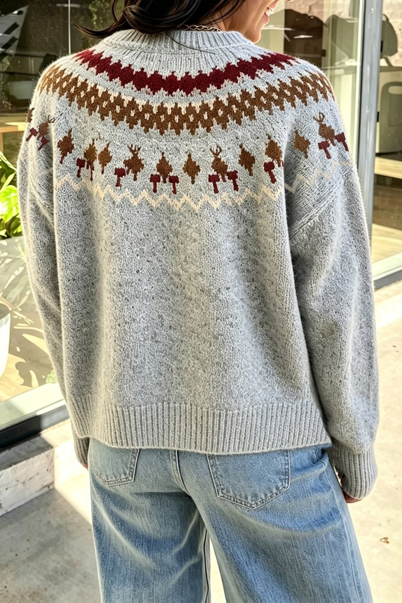 Back view of person in gray Fair Isle sweater with brown-burgundy yoke and blue jeans.